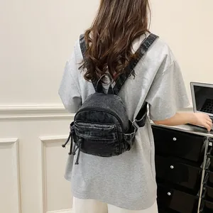 Casual dark wash denim mini backpack for women worn by a model in a minimalist setting