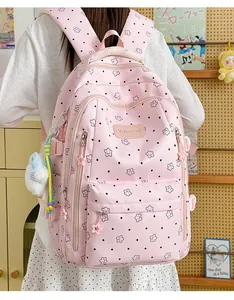Detailansicht der Rückseite eines rosa Schulrucksacks mit Sternenmustern und Plüsch-Anhängern