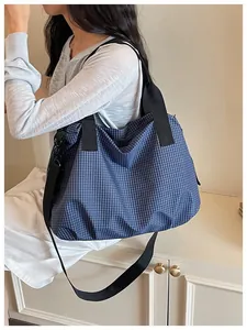 Detail view of large navy checkered nylon tote bag worn by a model for daily commuting