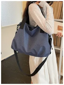 Blue grid pattern tote bag carried by a model standing next to a library bookshelf.