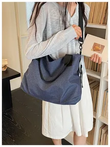 Woman carrying a large navy blue checkered nylon tote bag in a library bookstore scene