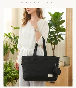 Modische große schwarze gesteppte Wickeltasche in einem Lifestyle-Innenraum gezeigt