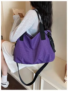 Detail view of a large purple checkered nylon tote bag carried by a model indoors