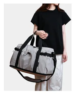 Grand sac de sport gris avec séparation humide, porté par un mannequin pour l'échelle.