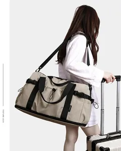 Vue latérale d'un grand sac de voyage kaki porté par un mannequin avec une valise