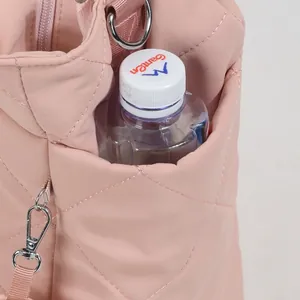 Close-up view of pink quilted diaper bag side pocket holding a water bottle cap