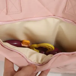Spacious interior detail of pink quilted diaper bag showing storage for baby items
