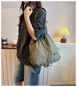 Grande borsa a tracolla in nylon verde oliva con coulisse in un ambiente di casa