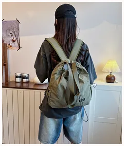Vista posteriore di una donna con zaino con coulisse in nylon impermeabile verde militare