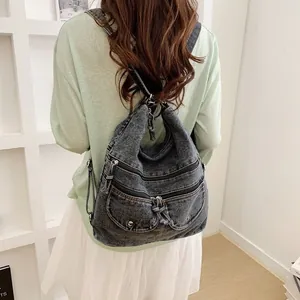 Back view of a woman wearing a stylish vintage grey denim backpack with multi-pocket design