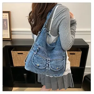 Vintage denim tote bag with multi-pocket design shown on model's shoulder.