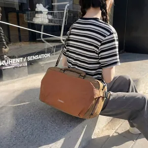 Close-up detail of a brown and tan outdoor sports travel bag being carried by a model.