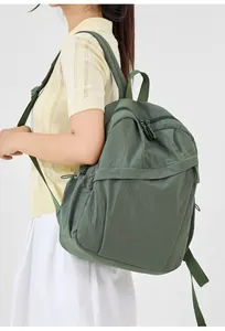 Detailed side view of a green nylon commuter backpack worn by a female model.