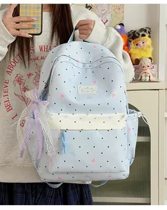 Detailed view of a cute blue polka dot backpack with a lace bow and heart patterns.