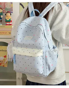 Cute light blue polka dot backpack with lace bow details worn by a student model