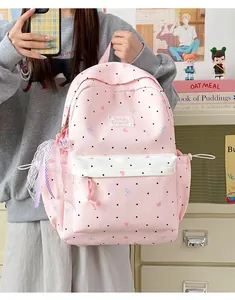 Detail view of pink polka dot backpack with decorative lace bow and ribbon accessory
