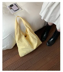 Large yellow nylon tote bag with floral embroidery in a lifestyle scene.