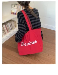 Red nylon canvas tote bag featuring 'Blessings' print and red plaid strap detail