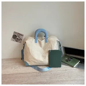 Grande borsa da viaggio in tela crema con cinghie e manici azzurri, mostrata con tablet