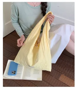 Detail view of a yellow nylon tote bag with flower embroidery held by a model