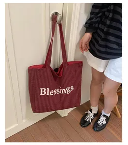 Close-up detail of a large red checkered canvas tote bag with Blessings embroidery