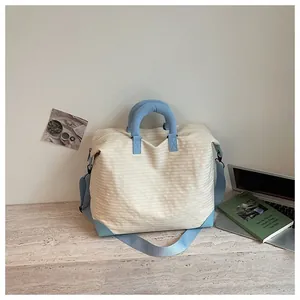 Borsa da viaggio minimalista a righe crema e blu in un accogliente ambiente interno.