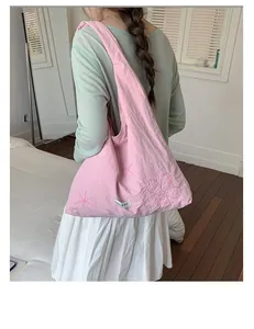 Casual pink nylon tote bag with floral embroidery worn by a model over the shoulder.