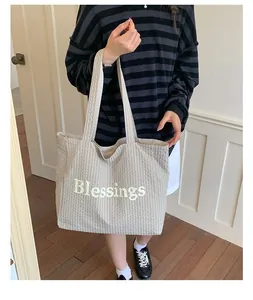 Detail of large checkered tote bag with Blessings letter print held by model