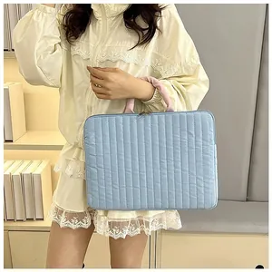 Modella asiatica porta a mano una custodia trapuntata per laptop azzurra con manici rosa
