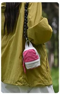 Close-up detail of a miniature pink and grey backpack pouch used as a trendy bag charm.