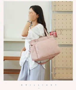 Large pink quilted diaper bag for mothers shown on model's shoulder in lifestyle setting