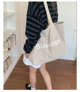 Large beige nylon tote bag with white Blessings print shown in a lifestyle setting