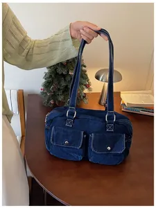Detail of a dark blue denim bowling bag with double front pockets and silver studs