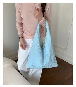 Light blue nylon tote bag featuring delicate floral embroidery detail in a lifestyle setting