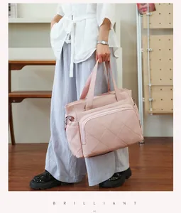 Pink quilted diaper bag held by a model in a stylish indoor setting