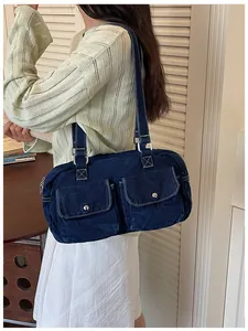 Side view of model wearing a dark blue denim bowling bag with white stitching details