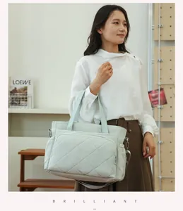 Asian model carrying a stylish quilted mint green diaper bag for travel and baby care