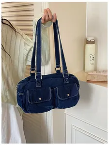 Close-up detail of a large capacity blue denim Boston shoulder bag with double front pockets.