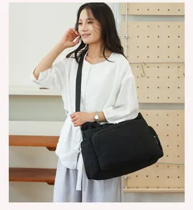 Asian model carrying a large black quilted multi-functional diaper bag in home setting
