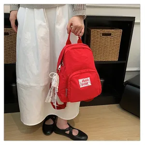 Close-up view of a vibrant red nylon backpack featuring sweet lace and pearl charms