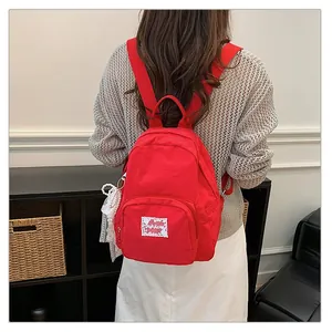 Rear view of a vibrant red minimalist backpack worn with a grey knit sweater