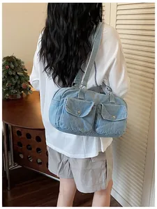 Detail view of a large denim Boston bag worn over the shoulder in a lifestyle setting.