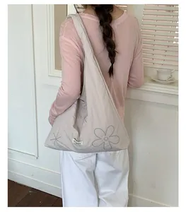 Large beige nylon tote bag with floral embroidery shown on a model in a bright room