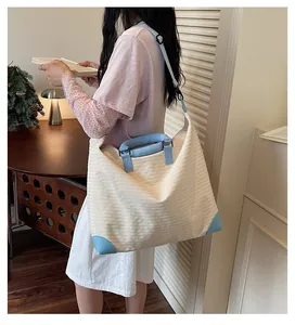 Grande borsa da viaggio leggera in tela indossata da una modella in un ambiente interno