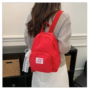 Detailed back view of a vibrant red casual backpack with lace and pearl charms.