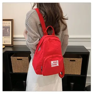 Macro view of a vibrant red backpack with a decorative lace-edged brand patch on the back
