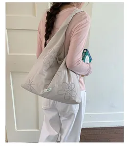 Young woman in a pink top carrying a large beige nylon tote bag with flower embroidery