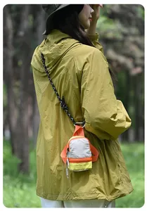 Detailed view of mini storage bag for earphones and coins worn outdoors with lanyard.