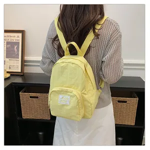 Back view of a minimalist yellow backpack worn by a student in a stylish indoor setting