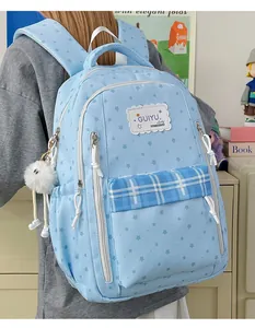 Detail of a light blue star print backpack with a plaid pocket and a cute plush charm accessory